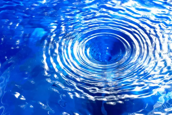 small water vortex or swirl, causing circular waves on the surface