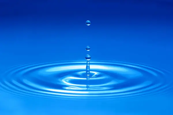 water drop dripping on a water surface, causing circular waves