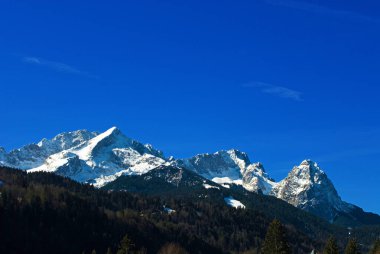 İlkbaharda karla kaplı Wetterstein dağları, solda Alpspitze, ortada Zugspitze ve sağda Waxenstein, Klais, Bavyera, Almanya 'da görüldü.