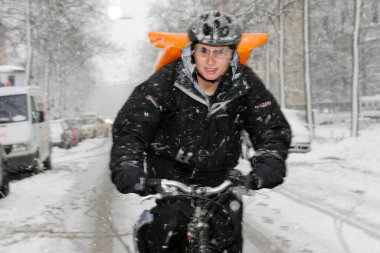Munich, Bavaria, Germany, February 15th 2005, a bicycle courier in winter with courier bag fights his way over snowy roads clipart