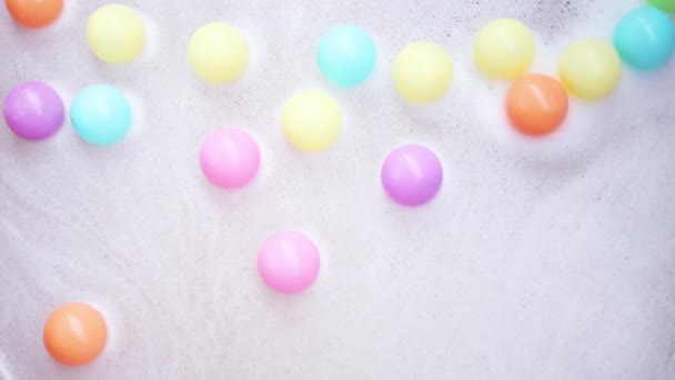 色彩斑斓的小塑料球在水面上漂浮的背景 肥皂泡和色彩斑斓的塑料球 — 图库视频影像