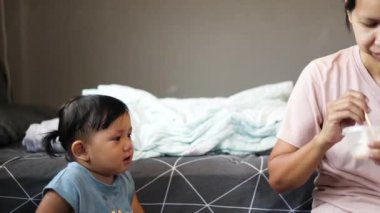 Gülümseyen anne ve oğlu evde kahvaltı yapıyor. Yavaş yaşam, mutlu aile anları. Anne oğlunu besliyor..