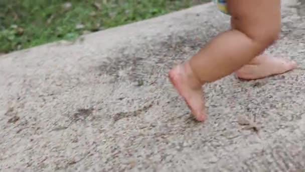 ベアフット トッドラー ボーイ ウォーキング パスウェイ 赤ん坊の足は汚れたコンクリートおよび緑の草の床で歩きます — ストック動画