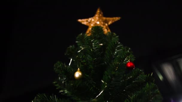 女性の手は お祝いの装飾されたクリスマスツリーに繊細な装飾を掛ける — ストック動画
