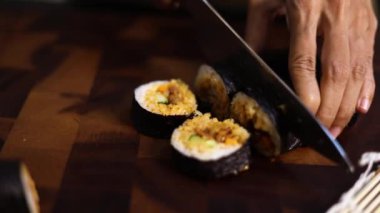 Kadın eli, Kore yosunlu pirinç rulosu veya kimbap dilimlemek için keskin bıçak kullanıyor..