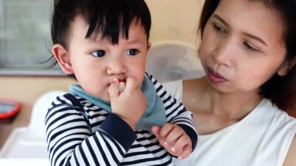 息子を抱えている母親がソーセージを食べている — ストック動画