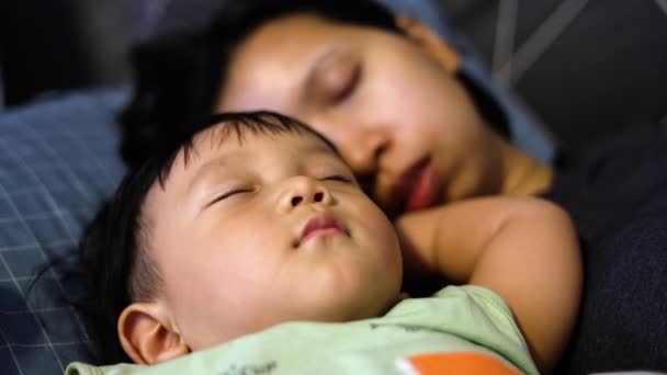 赤ん坊はベッドでママと寝ている かわいい少年と母親が寝室に横たわっている 日中は安らかに眠る 子供と母親の安全な睡眠 — ストック動画