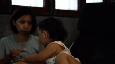 Dağınık suratlı küçük çocuk evde sağlıklı yiyecekler yiyor. Anne, bebeğini kaşıkla besliyor..