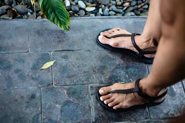 Female feet in sandals on the stone floor. Footwear for daily usage.