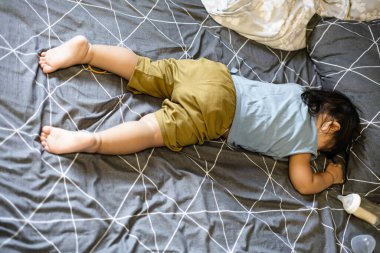 Küçük bir çocuk yatakta yüzüstü yatıyor..