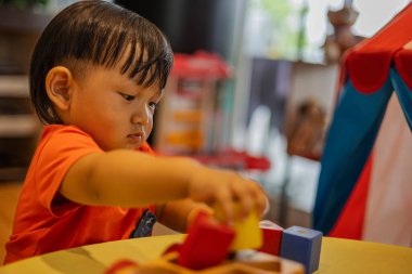 Masanın üzerinde renkli geometrik oyuncaklarla oynayan küçük bir çocuk. Renkli ahşap çocuk blokları.