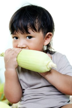 Taze mısır koçanı yiyen çocuğun yakın plan portresi. Ev yapımı organik yiyecekler. Vegan çocuklar için beslenme