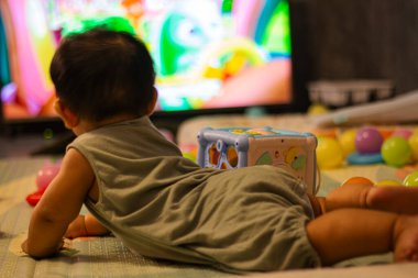 Vücut kıyafetli bebek, eğitim ve yaşam tarzında reklam ve duvar kâğıdı için arka planda, yumuşak bir minderin üzerinde emekliyor..