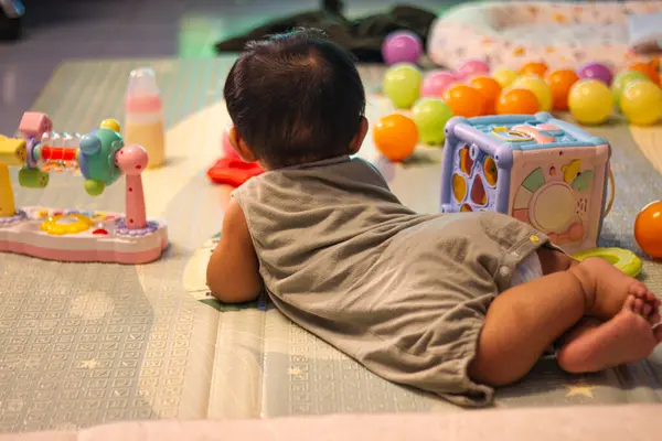 Vücut kıyafetli bebek, çocukların reklam ve duvar kâğıdı ve yaşam tarzı sahnesi için arka planda, yumuşak bir minderin üzerinde emekliyor..