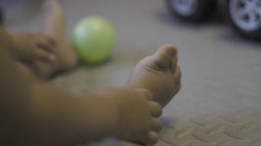Toddler 's Feet' in Yerde Oturan Ayakları 'nın yakın çekimi, belgesel için video görüntüleri ve yaşam tarzı sahnesinde sinematiktir..