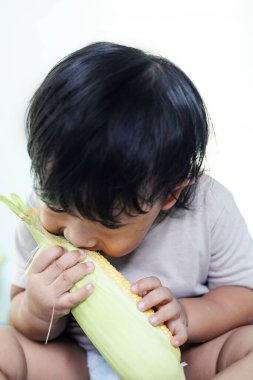 Çocuk Bitting Fresh Corn, Reklam için arka plan ve yiyecek ve içecek yaşam tarzı için duvar kağıdı.