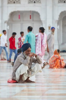 Amritsar, Punjab, Hindistan - 28 Ekim 2019 - Altın Tapınak yerleşkesinin önündeki mermer zeminde oturan yaşlı Sikh adam 
