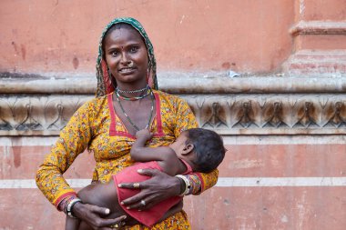Jaipur, Rajasthan, Hindistan - 18 Ekim 2019 - Hawa Mahal yolunda çocuğunu tutan Hintli kadının portresi 