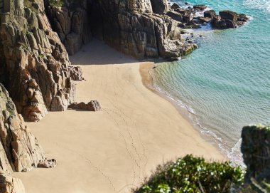 Porthcurno, Cornwall, İngiltere - Güneşli bir günde kayalar ve okyanusla Pedn Vounder Sahili 'nin en iyi manzarası