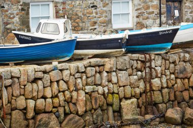 Mousehole, Cornwall, UK - Port wall with fishing boats on top at low tide clipart