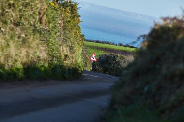 Cornwall, İngiltere - Tipik Cornwall manzarasında önümüzde virajlı yol olduğuna dair trafik işareti. 