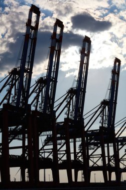 Hamburg limanında liman vinçlerinin siluetleri gökyüzüne karşı