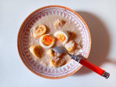 Beyaz arka planda izole edilmiş bir tabakta yulaf lapası, yumurta ve muzlu. Sağlıklı kahvaltı kavramı. 