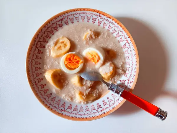 Beyaz arka planda izole edilmiş bir tabakta yulaf lapası, yumurta ve muzlu. Sağlıklı kahvaltı kavramı. 