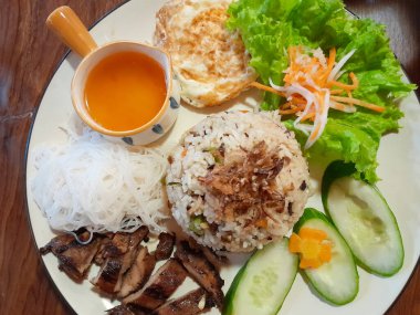 Kızarmış tavuklu Vietnam yemeği, pirinç vermicelli, omlet, ahşap masada izole edilmiş sebzeler. Üst görünüm.