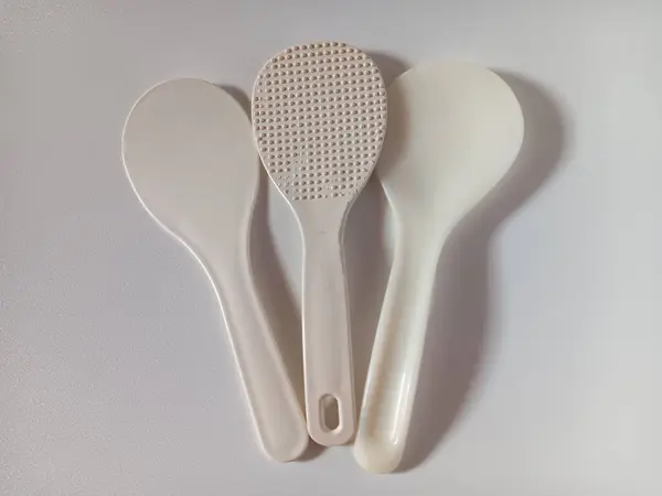 Beyaz arka planda beyaz plastik pirinç kepçesi.