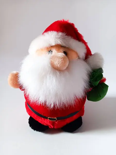 Beyaz arka planda yeşil paketi olan Noel Baba bebeği..