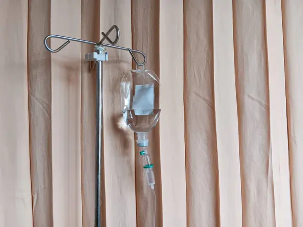 Hastanede fildişi çizgili perdelere karşı hastaya serum damlatıyor..