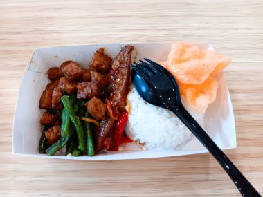 Tatlı soya tongkol komo namı diğer küçük ton balığı, Endonezya usulü kızarmış Tempeh, kızarmış yeşil fasulye, ahşap arka planda izole edilmiş yemek kutusunda beyaz pirinçli havuç..