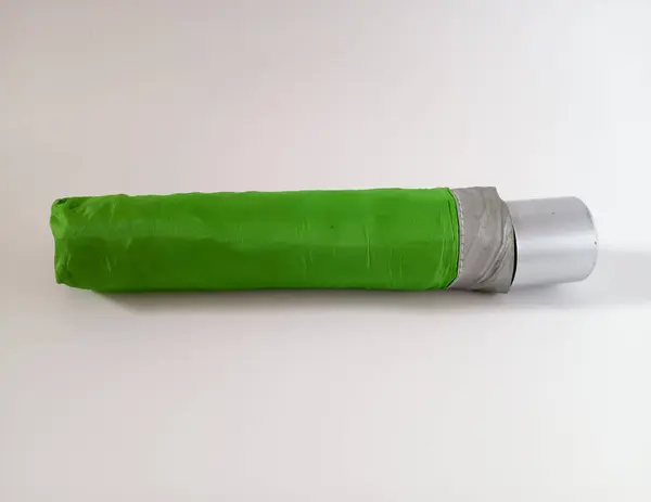 Beyaz arka planda izole edilmiş yeşil küçük katlanabilir şemsiye. Yağmurlu mevsim koruma kavramı. 