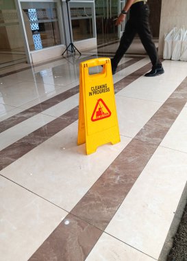 Dikkat, zemin ıslak sarı uyarı panosu, binanın önündeki seramik fayansların temizlenmesi devam ediyor..
