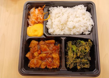 Japon bento seti sarımsaklı tavuk teriyaki, çıtır ıspanak, salata ve ahşap zemin üzerinde beyaz pirinç..