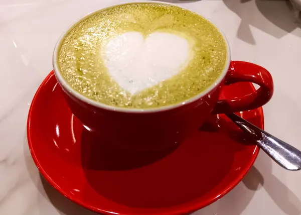 Kırmızı bardakta sıcak kibrit sütlü kahve beyaz arka planda izole edilmiş..