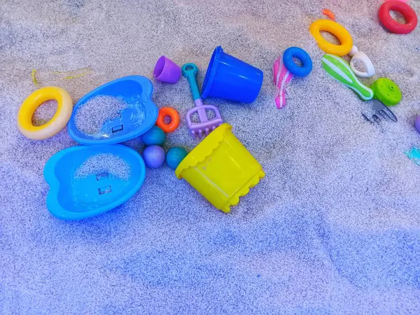 Kapalı alandaki çocukların oyun parkında duran kumsal kovası oyuncakları ve renkli yüzükler..