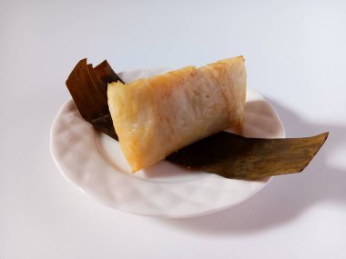 Arem-arem, muz yaprağına sarılmış, içi doğranmış tavuk ve doğranmış sebzelerle dolu, beyaz arka planda izole edilmiş bir Endonezya usulü sıkıştırılmış pirinç keki..