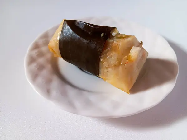 Arem-arem, muz yaprağına sarılmış, içi doğranmış tavuk ve doğranmış sebzelerle dolu, beyaz arka planda izole edilmiş bir Endonezya usulü sıkıştırılmış pirinç keki..