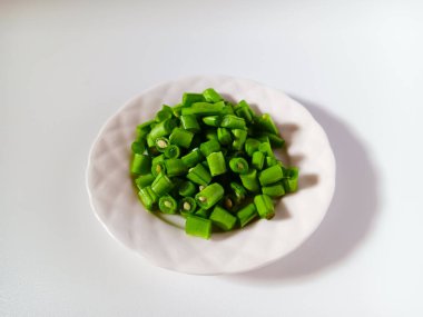 Beyaz arka planda izole edilmiş bir tabakta taze doğranmış yeşil fasulye..