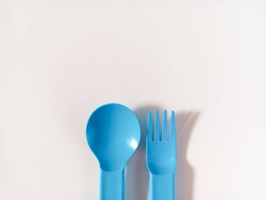 Mavi plastik kaşık ve çatal beyaz arka planda izole edilmiş. Metin için alanı kopyala.
