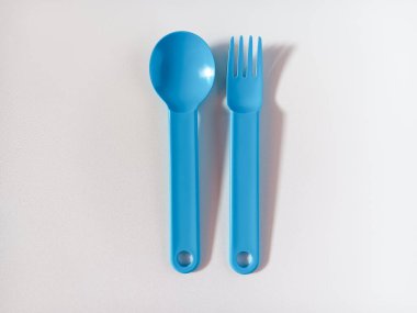 Beyaz arkaplanda izole edilmiş mavi plastik kaşık ve çatalı kapat.
