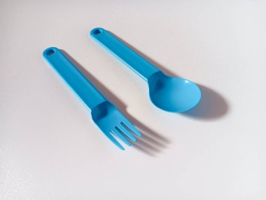 Beyaz arkaplanda izole edilmiş mavi plastik kaşık ve çatalı kapat.