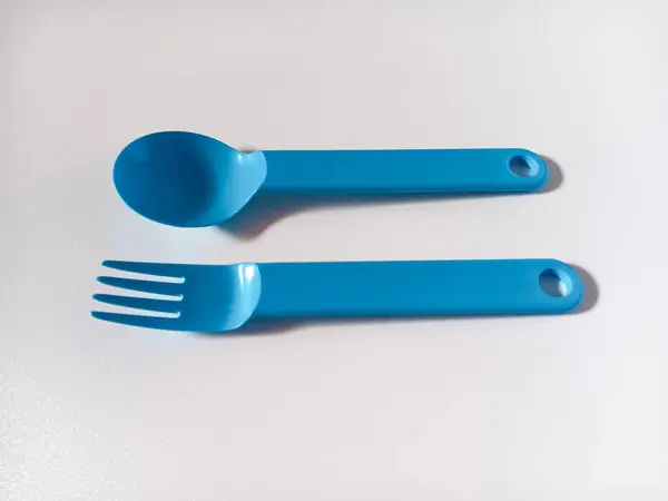 Beyaz arkaplanda izole edilmiş mavi plastik kaşık ve çatalı kapat.