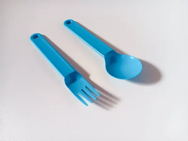 Beyaz arkaplanda izole edilmiş mavi plastik kaşık ve çatalı kapat.