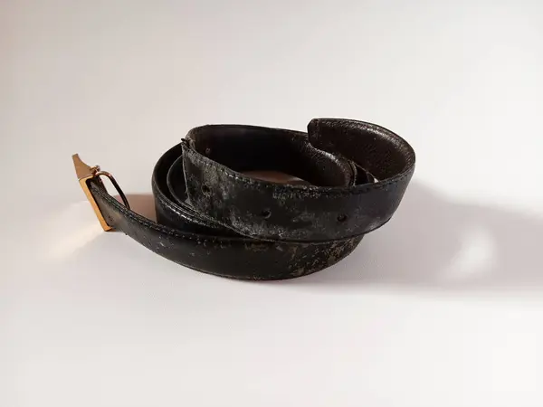 Beyaz arka planda soyulmuş deri yüzeyi ve altın tokası olan yaşlı adamların siyah kuşağı..