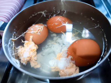 Kaynama sırasında yumurtalar çatladığı için yumurta sarısı akan bir tencerede haşlanmış yumurta..