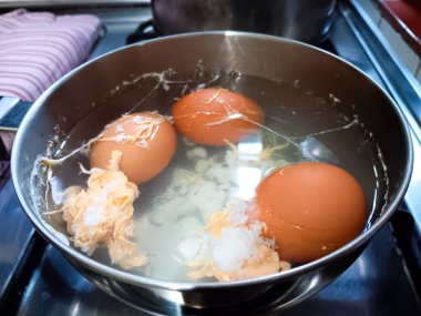 Kaynama sırasında yumurtalar çatladığı için yumurta sarısı akan bir tencerede haşlanmış yumurta..