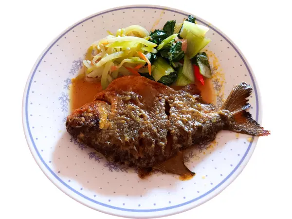 Endonezya yemeği, zerdeçal soslu kızarmış pomfret, beyaz arka planda izole bir tabakta kızarmış chayote ve pak choi. Sağlıklı gıda konsepti.